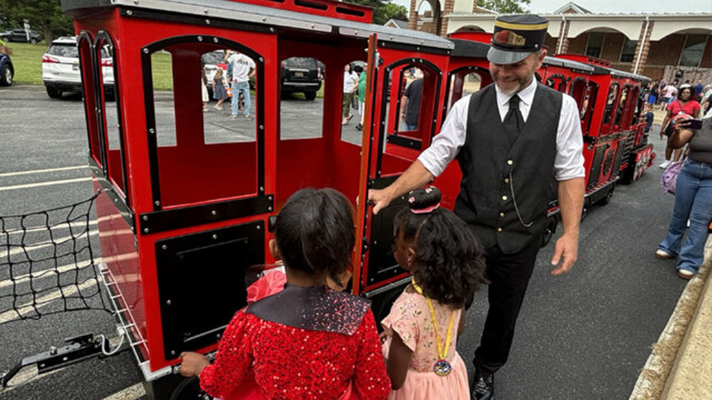 Wattman Maxi Express train driving through a US city park surrounded by families