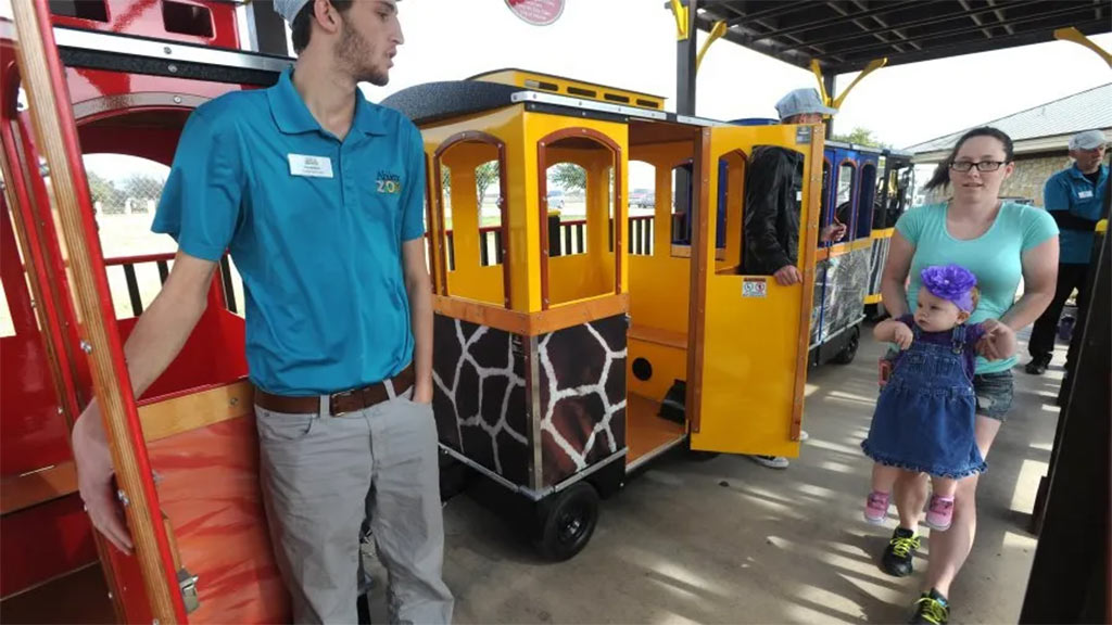 Wattman Maxi Express zoo train carrying children and parents near animal exhibits